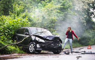 An Angry Young Woman With Smartphone By The Damaged Car After A Car Accident.