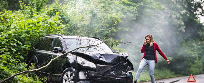 An Angry Young Woman With Smartphone By The Damaged Car After A Car Accident.