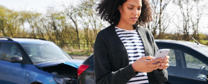 Female Driver Contacting Car Insurance Company On Mobile Phone After Road Traffic Accident