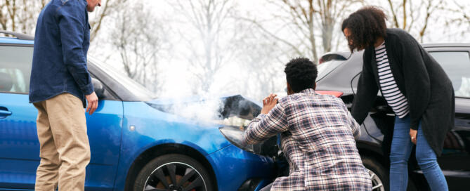 Young Couple Take Photos On Mobile Phone Of Damage To Car In Accident With Senior Driver