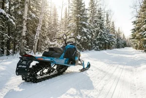 A snowmobile on a groomed trail in a Minnesota forest, representing legal services for snowmobile accident injuries and winter recreation safety.